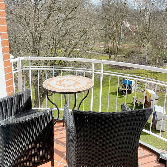 Doppelzimmer Loggia Loggia Doppelzimmer, auf der Loggia Sitzmöglichkeiten sowie ein runder Tisch, Blick in den Kurpark, im Kurpark stehen Bäume und Strandkörbe