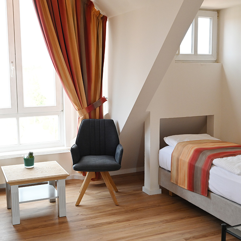 Kurpark-Suite Schlafzimmer Schlafzimmer in Kurpark-Suite, rechte Seite Bett, links daneben Fenster, davor Sitzmöglichkeit mit Tisch