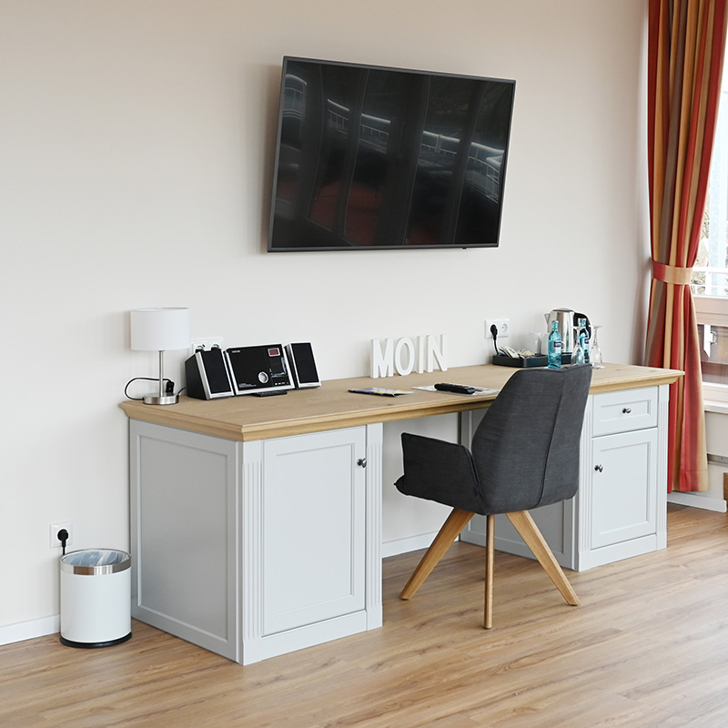 Ostsee-Suite Schreibtisch Schreibtisch mit Stuhl und Minibar in der Ostsee-Suite, auf dem Schreibtisch Welcome Tray Kaffee/Tee, Wasserkocher, Radio, neben dem Schreibtisch steht ein Papierkorb