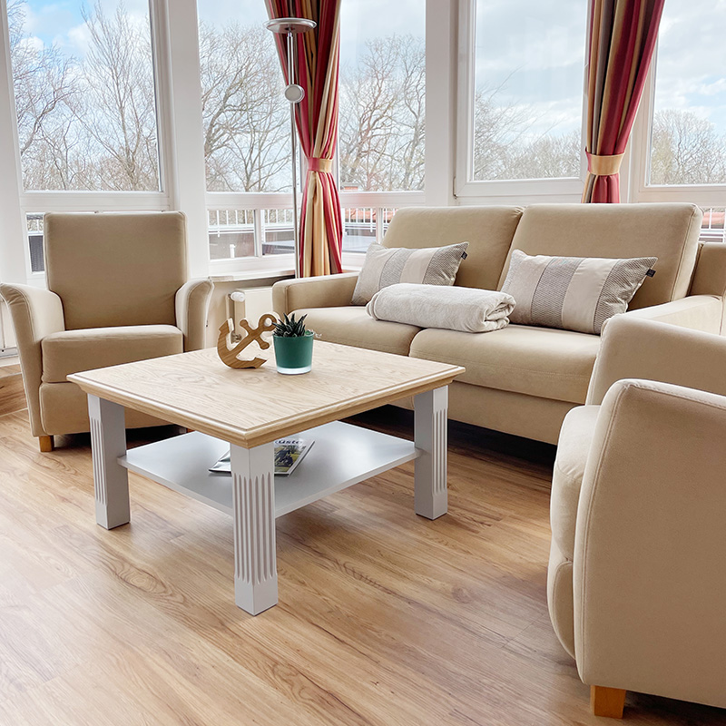 Ostsee-Suite Sitzbereich Sitzbereich Ostseesuite direkt an der Fensterfront, Sofa mit Kissen und Decke, zwei Sessel sowie Tisch mit Deko Anger und Pflanze