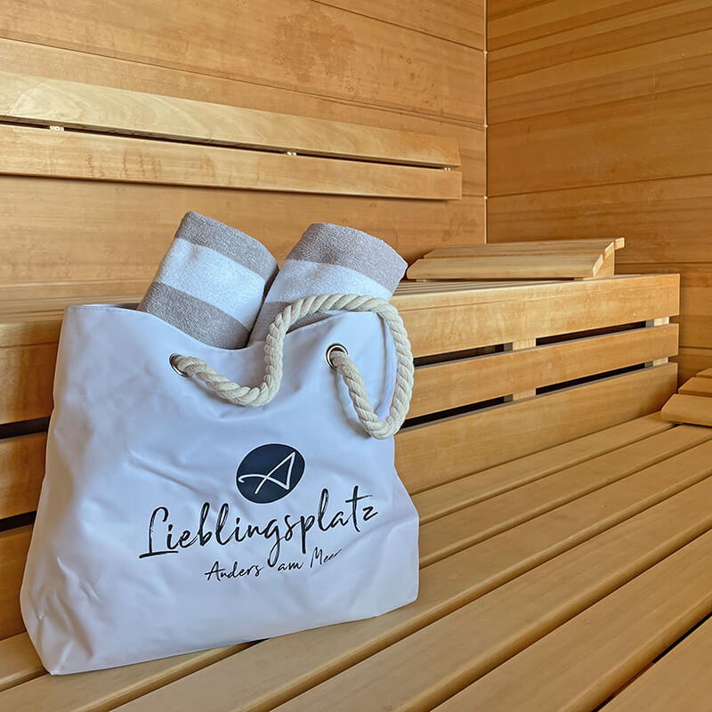 weiße Lieblingsplatz Tasche mit zwei gestreiften Handtüchern drinnen, auf der Bank in der Sauna