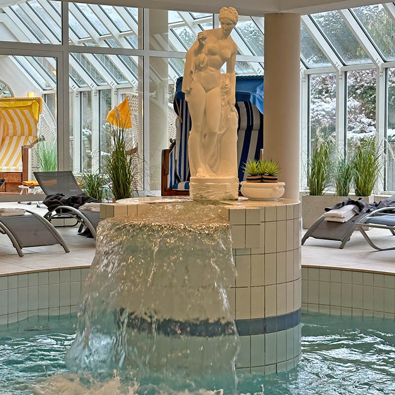 Wasserfall mit einer griechischen Statur oben drauf imSchwimmbad Hotel Hohe Wacht